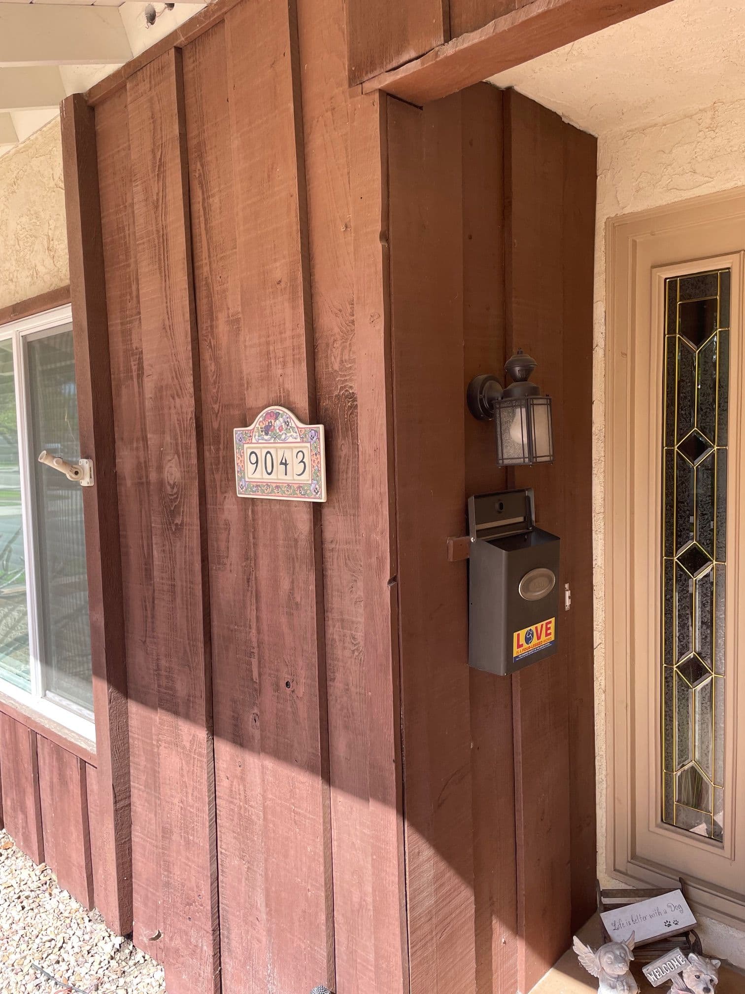 Wooden home exterior with house number 9043, lantern, and decorative mailbox labeled "LOVE."