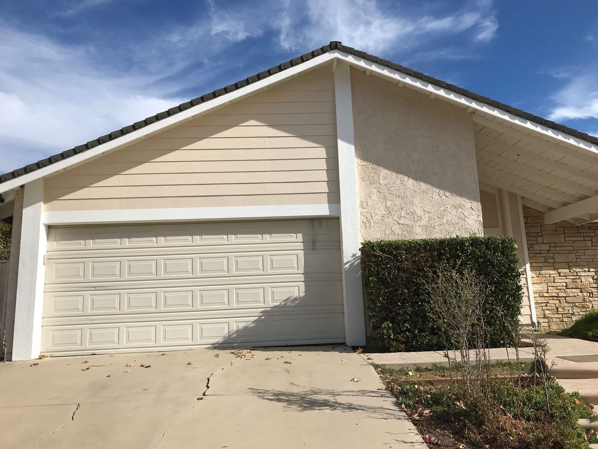Modern suburban house with a large garage, light exterior, and landscaped front yard.